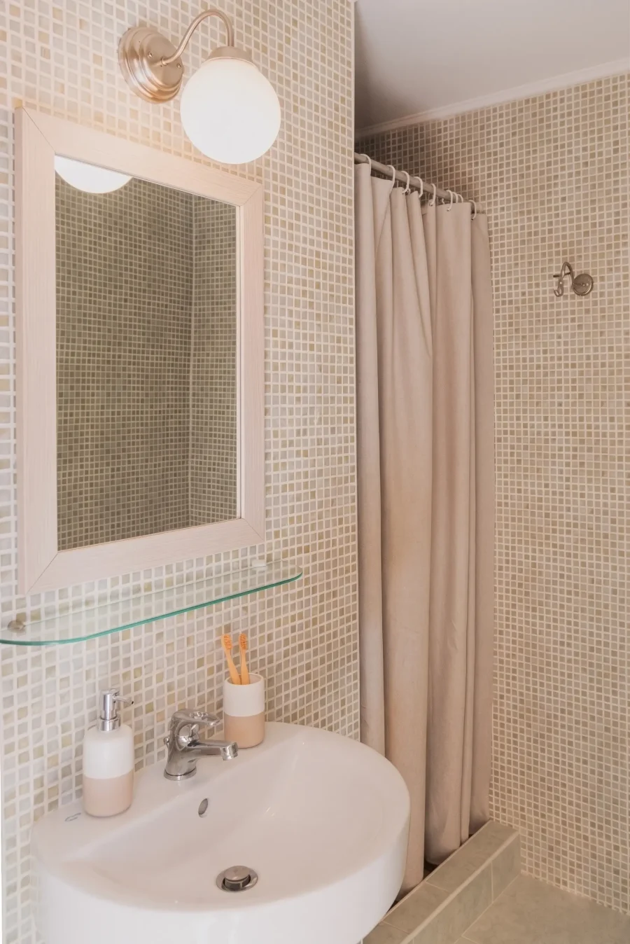 Clean, private bathroom in a Kamini Apartments Corfu rental, equipped with a large mirror, vanity lighting, and fresh amenities.