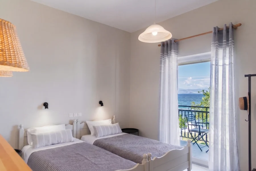 Self-catering studio accommodation in Kavos, Corfu, featuring twin beds with reading lights and a balcony overlooking the sea.