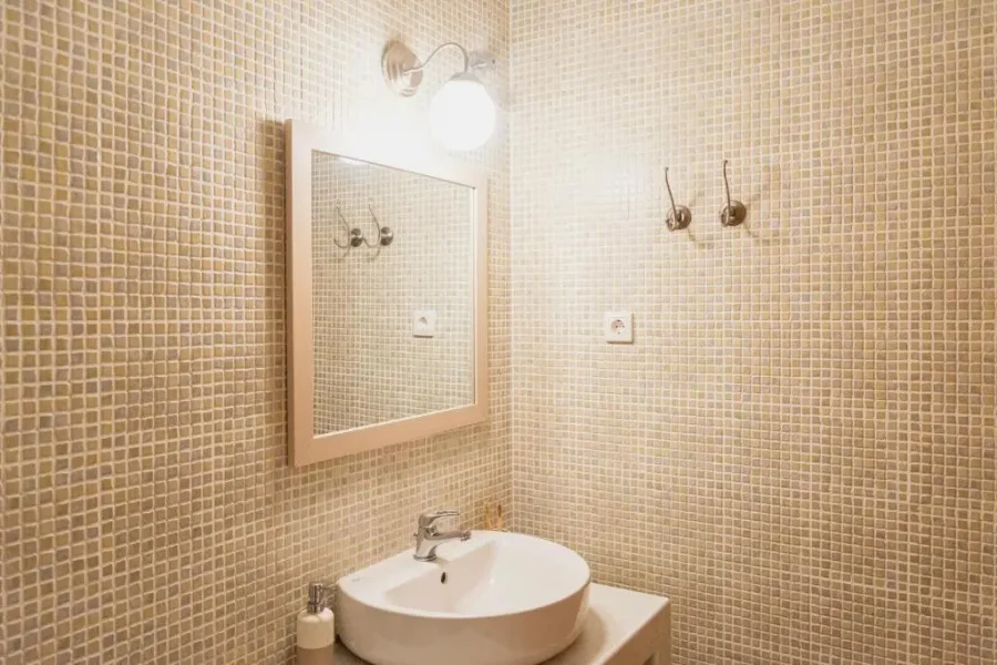 Private bathroom interior at Kamini Apartments Corfu featuring modern fixtures, a towel hook, and neutral tiled walls.