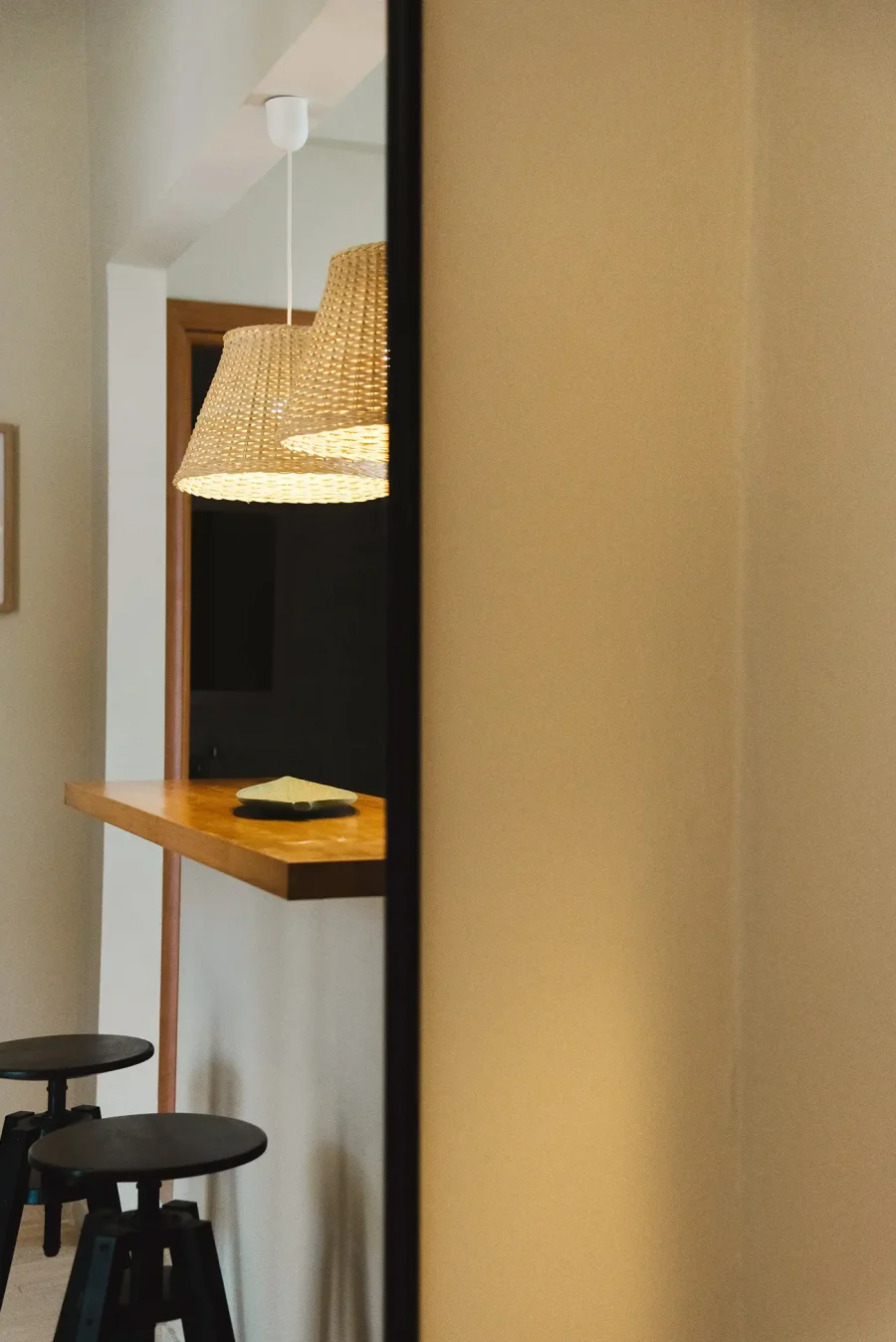 Mirror reflection of a modern breakfast bar and wicker pendant lights at Kamini Apartments Kavos, showing stylish Mediterranean interior design.